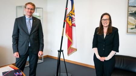 Ministerpräsident Daniel Günther und die isländische Botschafterin, Maria Marelsdottir, stehen nebeneinander und lächeln in die Kamera.